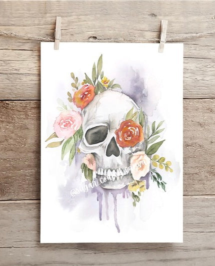 Skull with floral decorations on a white background, hanging on a wooden surface.